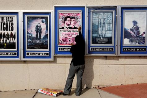 A poster for the movie The Interview is taken down by a worker after being pulled from a display case at a Carmike Cinemas movie theater, Wednesday, in Atlanta. Sony Pictures cancelled all release plans for the film which has been at the heart of an unprecedented act of cyberwarfare which U.S. officials link to North Korea. 