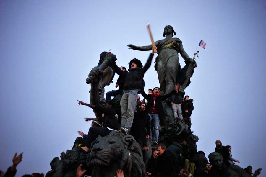 People gather atop a statue at Place de la Nation during a rally in Paris on Sunday. Hundreds of thousands gathered Sunday throughout Paris and cities around the world, to show unity and defiance in the face of terrorism that killed 17 people in France’s bleakest moment in half a century.