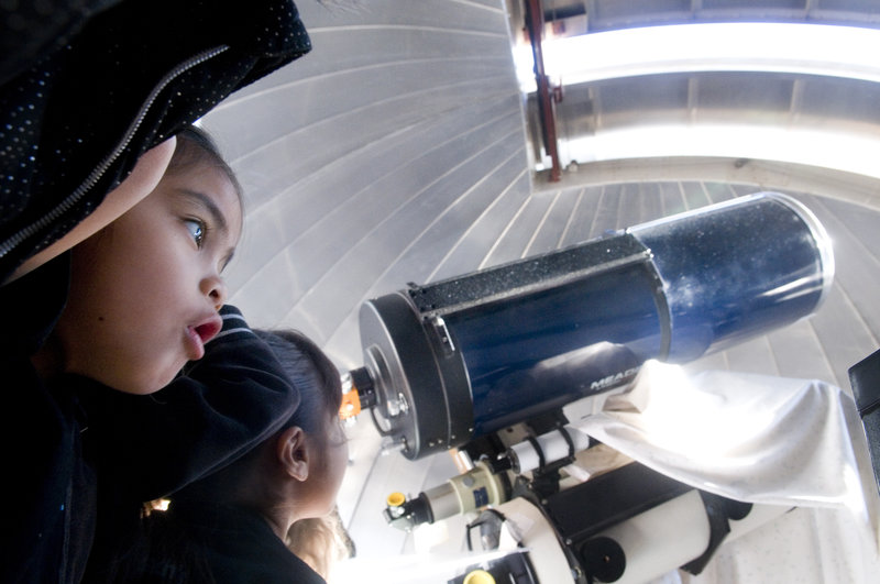 Zia Amba, a first grade student at the Academy for Academic Excellence watches the observatory doors move during the school's Astronomy Day Friday, Jan. 23, in Apple Valley, Calif.  