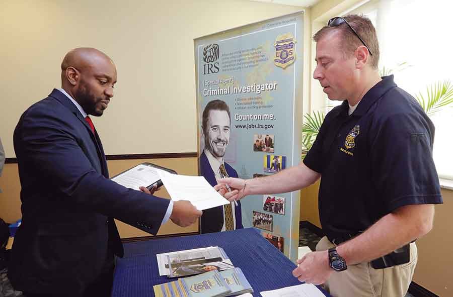 U.S. Marine Corps Veteran Arlington Robertson, of Fort Lauderdale, left, hands his resume to an Internal Revenue Service Special Agent, at the annual Veterans Career and Resource Fair in Miami. The Labor Department releases employment data for February on Friday.