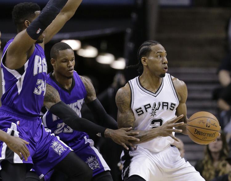 San Antonio Spurs’ Kawhi Leonard (2) drives past Sacramento Kings defenders Jason Thompson (34) and Ben McLemore (23) during the first half of an NBA basketball game, Wednesday, March 4, 2015, in San Antonio. 