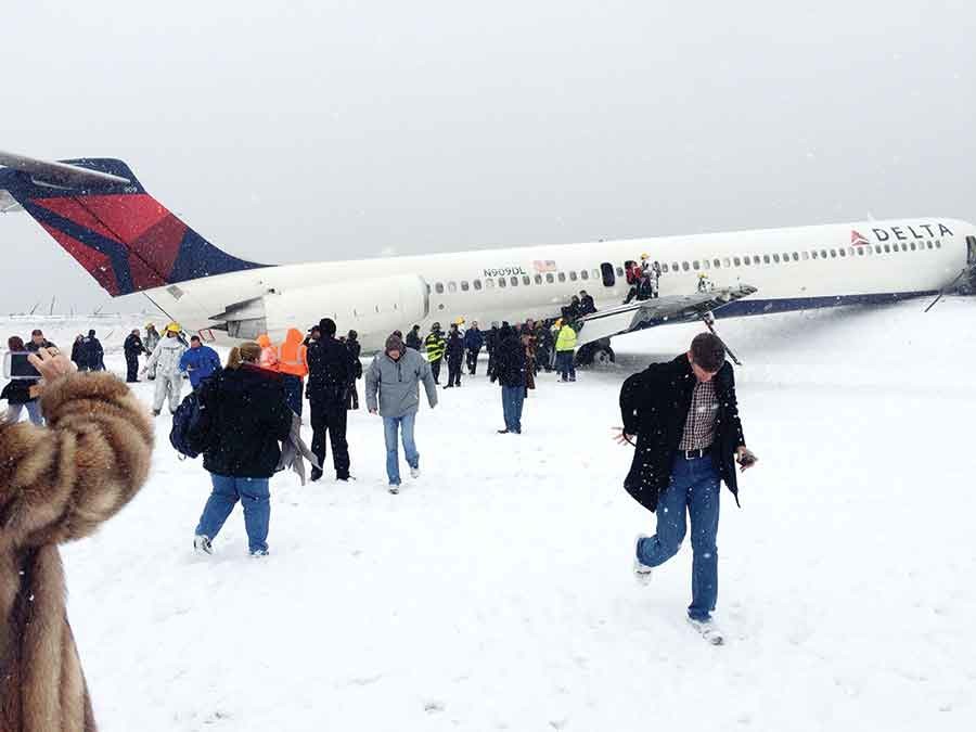 In this photo provided by passenger Amber Reid, passengers are evacuated after a Delta plane skidded off the runway while landing at LaGuardia Airport during a snowstorm, Thursday, March 5, 2015, in New York. Authorities said the plane, from Atlanta, carrying 125 passengers and five crew members, veered off the runway at around 11:10 a.m. before crashing through a chain-link fence and coming to rest with its nose perilously close to the edge of an icy bay. 