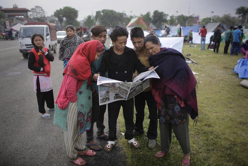Survivors of Saturdays earthquake read newspaper at a makeshift camp in Kathmandu, Nepal, Tuesday, April 28, 2015. 