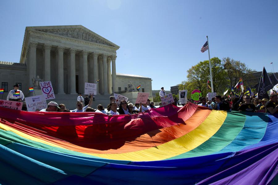 Demonstrators stand in front of a rainbow flag of the Supreme Court in Washington, Tuesday, April 28, 2015. The Supreme Court is set to hear historic arguments in cases that could make same-sex marriage the law of the land. The justices are meeting Tuesday to offer the first public indication of where they stand in the dispute over whether states can continue defining marriage as the union of a man and a woman, or whether the Constitution gives gay and lesbian couples the right to marry. 