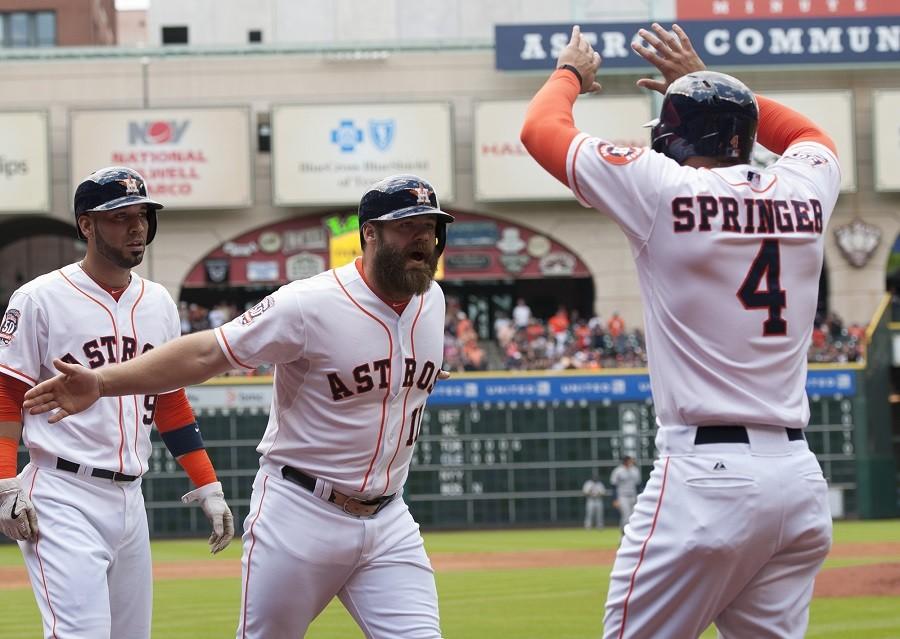 Houston Astros designated hitter Evan Gattis (11) celebrates his three-run home run against the Seattle Mariners with teammate George Springer (4) in the first inning of a baseball game on Sunday, May 3, in Houston.