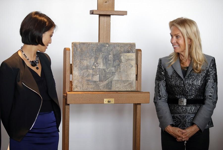 French Minister of Culture and Communication Fleur Pellerin, left, and Jane D. Hartley, U.S. Ambassador to France, right, pose next to La Coiffeuse, or The Hairdresser, a $ 15 million Picasso painting, found in New Jersey, during a presentation at Beaubourg Pompidou Center Museum in Paris, France, Thursday, Sept. 24. This Picasso artwork, painted in 1911, is going back on display in a Paris Museum after it disappeared from a French storage room more than a decade ago, then turned up in a package from Belgium to New York last year. 