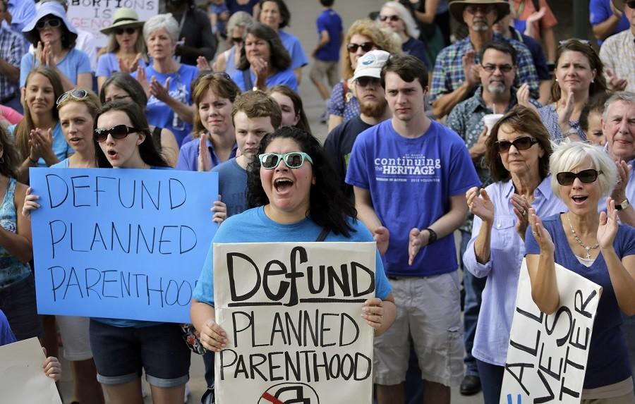 In this July 28, photo, Erica Canaut, center, cheers as she and other anti-abortion activists rally on the steps of the Texas Capitol in Austin, Texas, to condemn the use in medical research of tissue samples obtained from aborted fetuses. Texas announced Monday, Oct. 19, that it was cutting off Medicaid funding to Planned Parenthood clinics following undercover videos of officials discussing fetal tissue, potentially triggering a legal fight like the one unfolding in neighboring Louisiana. 