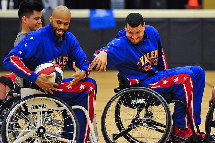 Globetrotters El Gato and Hawk attempt to control the ball well trying to navigate their wheelchairs.