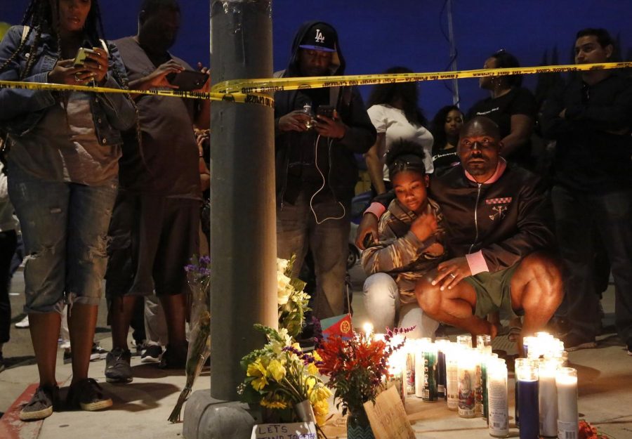 Haitian-French actor Jimmy Jean-Louis and his daughter Jasmin, 16, gather around candles set up across from the clothing store of rapper Nipsey Hussle in Los Angeles, on Sunday, March 31, 2019. Hussle, the skilled and respected West Coast rapper who had a decade-long success with mixtapes but hit new heights with his Grammy-nominated major-label debut album in 2018, was killed at the age of 33.