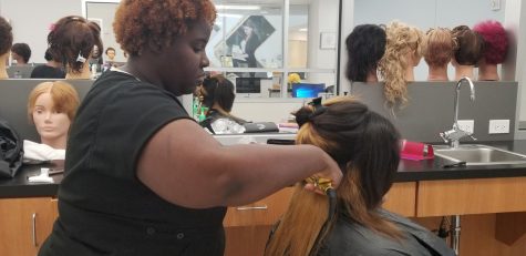HCC Cosmetology student Miesha Laurent performs a flat iron blowout to her client at HCC Southeast