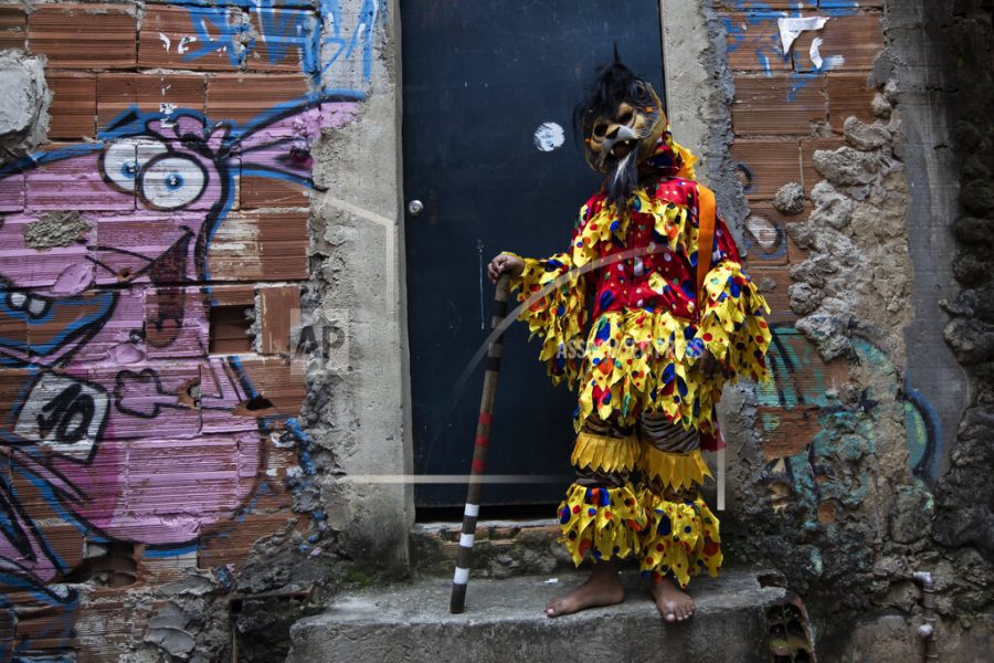 A boy dressed as a clown waits for the start of the meeting of the Kings Revelry groups in the Santa Marta favela, as part of cultural events celebrating Black Awareness month, in Rio de Janeiro, Brazil, Saturday, Nov. 13, 2021. (AP Photo/Bruna Prado)