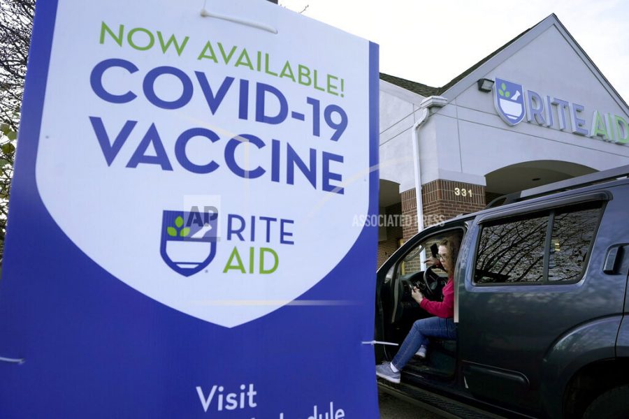 A woman is parked near a COVID-19 vaccine sign as she arrives at a Rite Aid pharmacy, Tuesday, Dec. 7, 2021, in Nashua, N.H. Even as the U.S. reaches a COVID-19 milestone of roughly 200 million fully-vaccinated people, infections and hospitalizations are spiking, including in highly-vaccinated pockets of the country like New England. (AP Photo/Steven Senne)