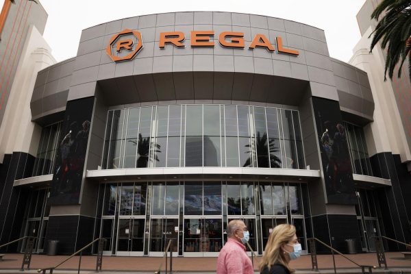 Two people walking by Regal Cinema theater during the pandemic. Movie theaters were closed at the time. 