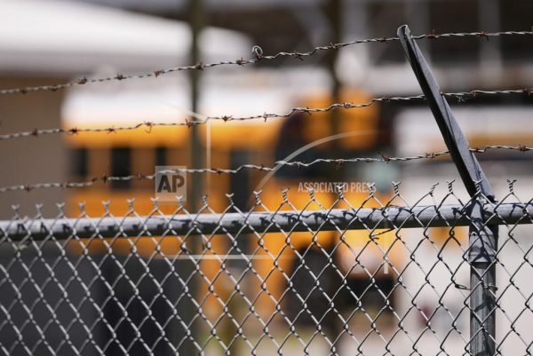 A school bus is seen behind a fence with barbed wire outside Ferriday High School in Ferriday, La., Thursday, May 22, 2025. 
